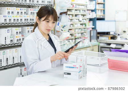 A woman working in a dispensing pharmacy 87986302