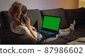 Woman sitting on couch working on laptop computer 87986602