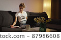 Young woman learning online class at night late makes note from laptop. 87986608