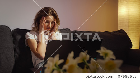 Woman working on laptop alone in dark living late at night 87986613