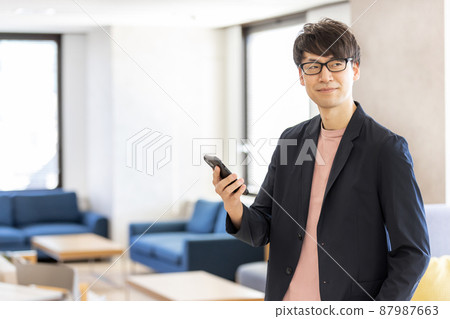 一位在聯合辦公空間中操作智能手機的商人 一位在聯合辦公空間中操作智能手機的商人 87987663