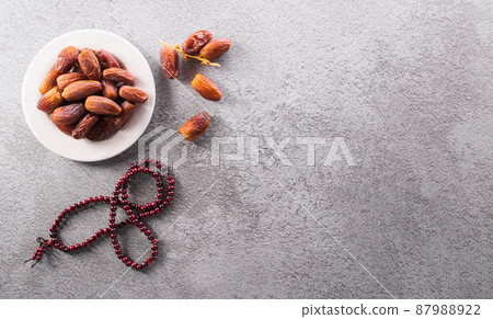Top view image of Ramadan Kareem decoration, dates fruit and rosary beads on dark stone background. Top view image of Ramadan Kareem decoration, dates fruit and rosary beads on dark stone background. 87988922