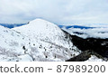 A snowy mountain covered with white snow with a sea of clouds in the distance 87989200