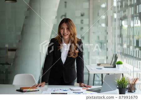 Portrait of attractive Asian Businesswoman working on laptop for marketing plan with paperwork Portrait of attractive Asian Businesswoman working on laptop for marketing plan with paperwork 87991670