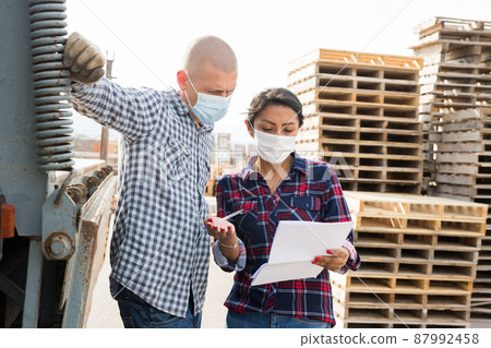 Woman manager in face mask discussing order list with man worker 87992458