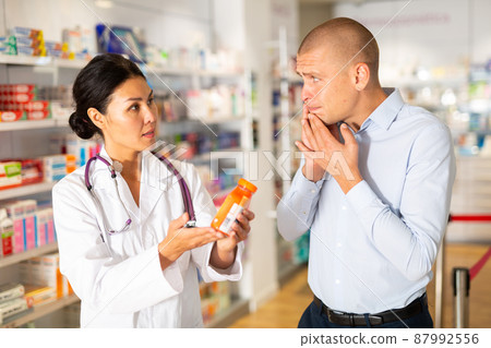 Man asks to help pharmacist choose medicine for toothache Man asks to help pharmacist choose medicine for toothache 87992556