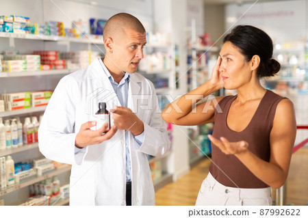 Woman buyer asks for help of pharmacist to choose medicine for headache closeup Woman buyer asks for help of pharmacist to choose medicine for headache closeup 87992622