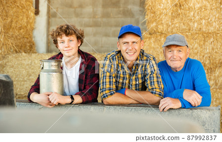 Various aged farmers standing inside hay bales storage 87992837