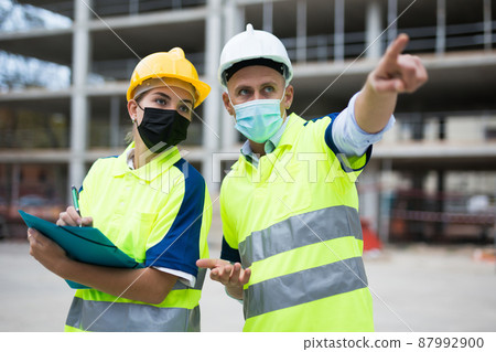 Civil engineers in masks checking work process Civil engineers in masks checking work process 87992900