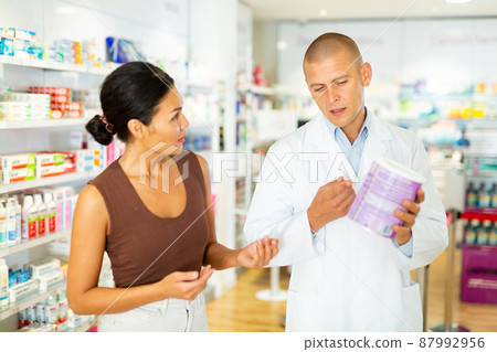 Female buyer consults the pharmacist which lotion or ointment to buy at pharmacy Female buyer consults the pharmacist which lotion or ointment to buy at pharmacy 87992956