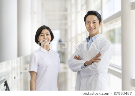 一位身穿白大褂的男女醫務工作者,看著鏡頭,微笑著 一位身穿白大褂的男女醫務工作者,看著鏡頭,微笑著 87993497