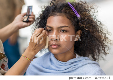 Stylist is putting make up on black woman eyebrows with the eyebrows brush 87996621