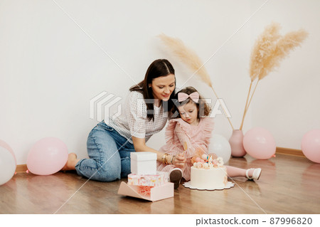 A young mother gives a birthday cake to her charming daughter 87996820