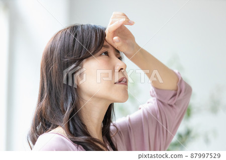 一位身體狀況不佳的婦女,穿著房間的衣服,把手放在額頭上 一位身體狀況不佳的婦女,穿著房間的衣服,把手放在額頭上 87997529