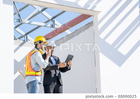 Engineers are discussing data working and tablet with architectural project at new construction site 88000025