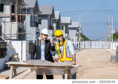 Architectural engineer meeting and working with blueprints at construction site,discussing,designing 88000039