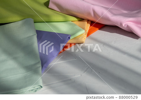 Stack of colorful cotton fabric against grey background, slow fashion and home sewing concept Stack of colorful cotton fabric against grey background, slow fashion and home sewing concept 88000529