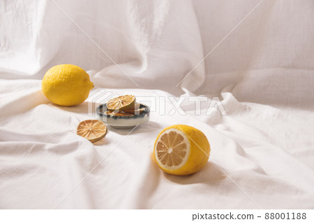Yellow lemons and dried fruit slices on a bright white background showing the delicate April Spring time aesthetics and sustainable living concept 88001188