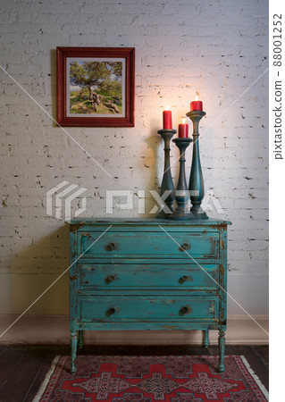 Green vintage cabinet, candlesticks and hanged painting on bricks wall Green vintage cabinet, candlesticks and hanged painting on bricks wall 88001252