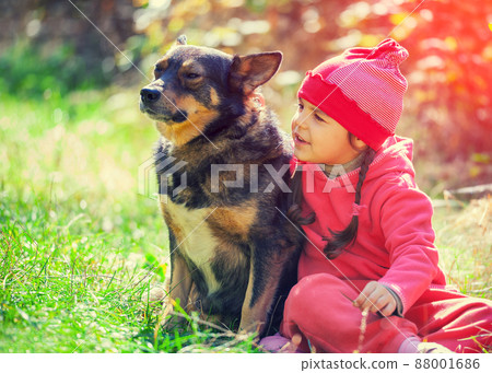 Happy little girl playing with dog in the forest 88001686