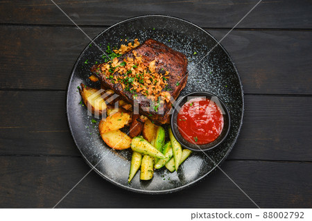 Overhead view of grilled pork ribs with potato wedges and cucumber 88002792
