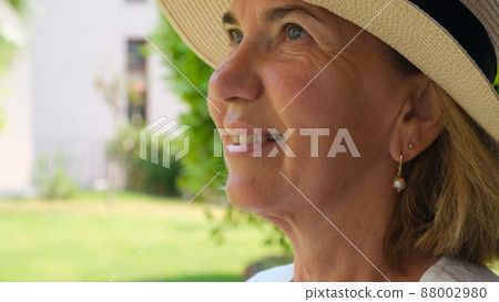 portrait of a mature woman 55-60 years old with a toothy smile in a sun-protective straw hat 88002980