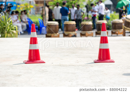 traffic sign. Orange cone with white stripes at road background.  88004222