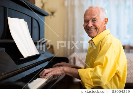 Elderly composer composes music and plays piano at home Elderly composer composes music and plays piano at home 88004239