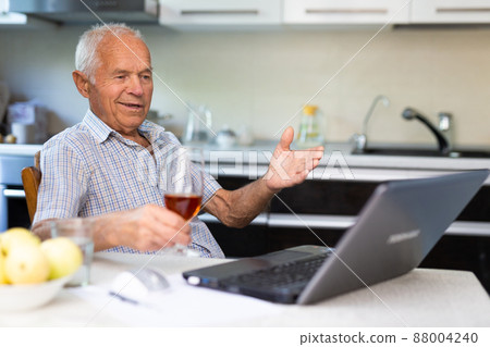 Senior man with glass of brandy and laptop Senior man with glass of brandy and laptop 88004240