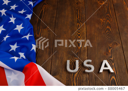 the word USA laid with silver metal letters on wooden board surface under crumpled flag of United States of America the word USA laid with silver metal letters on wooden board surface under crumpled flag of United States of America 88005467