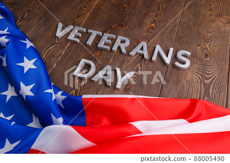 the words veterans day laid with silver metal letters on wooden board surface with crumpled usa flag 88005490