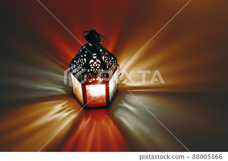 Ornamental Moroccan, Arabic lantern on the table. Burning candle at night. Colorful light rays. Greeting card for Muslim community holy month Ramadan Kareem. Festive blurred background. Top view. Ornamental Moroccan, Arabic lantern on the table. Burning candle at night. Colorful light rays. Greeting card for Muslim community holy month Ramadan Kareem. Festive blurred background. Top view. 88005866