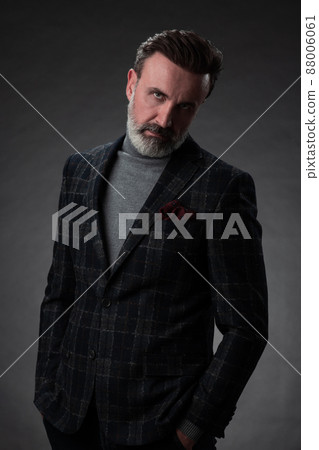Portrait of a stylish elegant senior businessman with a beard and casual business clothes in photo studio isolated on dark background gesturing with hands Portrait of a stylish elegant senior businessman with a beard and casual business clothes in photo studio isolated on dark background gesturing with hands 88006061