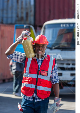 African American Container Warehouse Worker. Foreman carrying oil gallons. 88006097