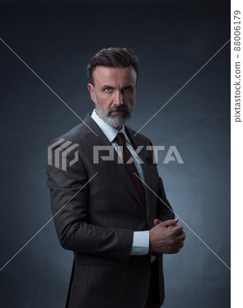 Portrait of a stylish elegant senior businessman with a beard and casual business clothes in photo studio isolated on dark background gesturing with hands Portrait of a stylish elegant senior businessman with a beard and casual business clothes in photo studio isolated on dark background gesturing with hands 88006179
