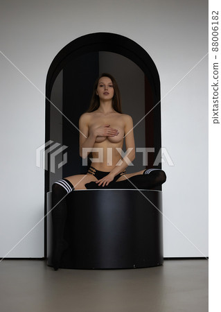 Sensual topless woman covering breast sitting on pouf Sensual topless woman covering breast sitting on pouf 88006182