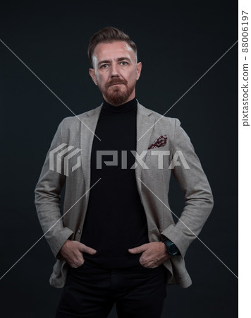 Portrait of a stylish elegant senior businessman with a beard and casual business clothes in photo studio isolated on dark background gesturing with hands 88006197