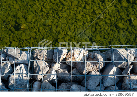Wall of stones held by a metal mesh. Wide panoramic texture for background and design. Wall of stones held by a metal mesh. Wide panoramic texture for background and design. 88009597