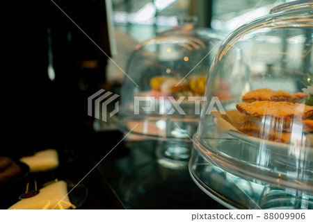 Pastry in cake glass stand display with cover dome in coffee shop or bakery shop. Pastry in cake stand on counter for buffet service in the restaurant. Pastry and coffee cafe for service customers. 88009906