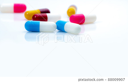 Selective focus on blue-white antibiotic capsule pills on white background. Prescription drugs. Colorful capsule pills. Antibiotic drug resistance concept. Pharmaceutical industry. Superbug problems. 88009907
