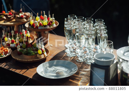 Table of various snacks, sandwiches, strawberries and champagne glasses. Buffet for wedding guests 88011805