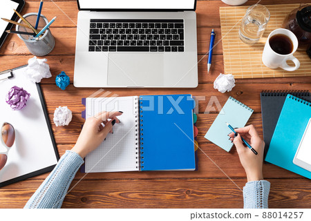 Business woman writing in notebook at office desk 88014257