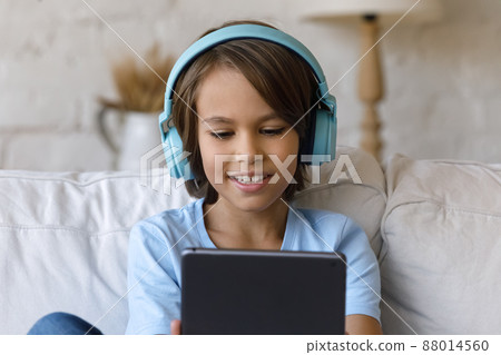 Attractive little boy wear headphones have fun using digital tablet 88014560