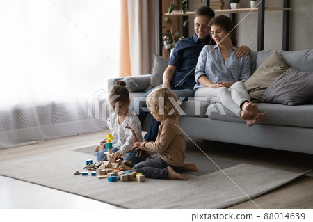 Relaxed young c parents watching small children playing at home. Relaxed young c parents watching small children playing at home. 88014639