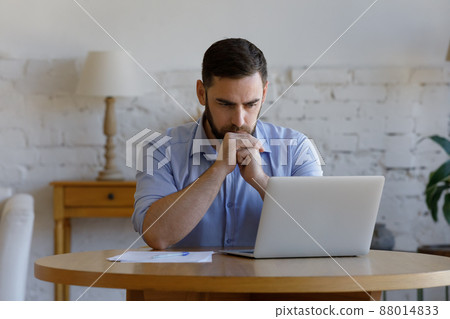 Serious man read e-mail on laptop looks concerned or puzzled 88014833