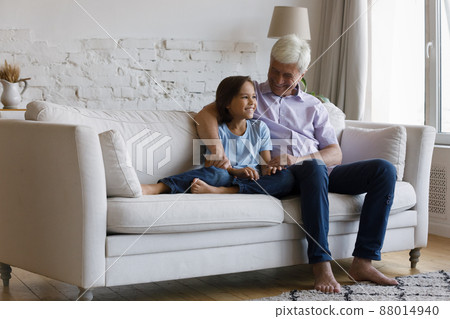 Older grandfather hugs grandson sit on sofa enjoy pleasant conversation Older grandfather hugs grandson sit on sofa enjoy pleasant conversation 88014940