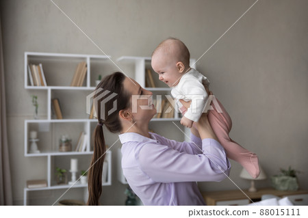Cheerful happy new mom lifting adorable baby 88015111