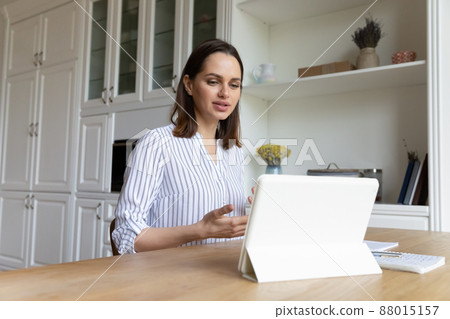 Woman use digital tablet talks on video conferencing application 88015157