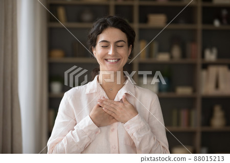 Grateful happy young Hispanic woman folded hands on chest. Grateful happy young Hispanic woman folded hands on chest. 88015213