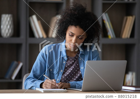 Serious young African Black student girl writing notes at laptop Serious young African Black student girl writing notes at laptop 88015218